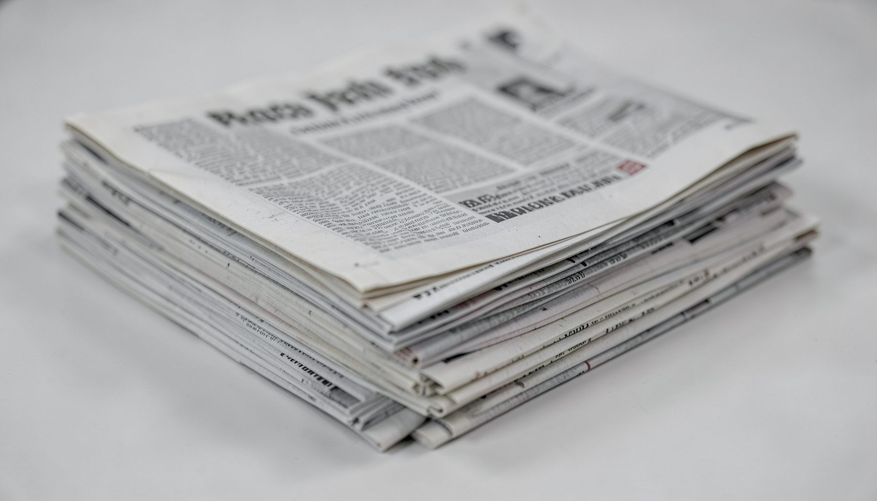 A stack of newspapers with a muted gray and off-white palette, suggesting breaking health policy news